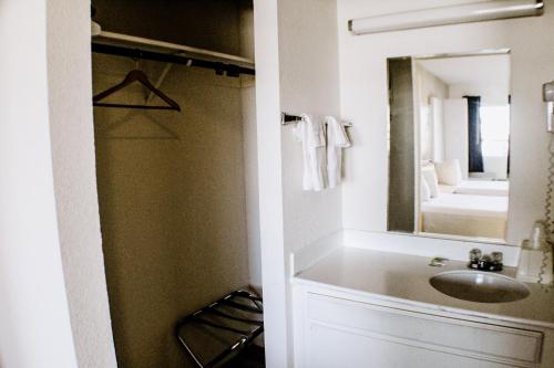 een badkamer met een wastafel en een spiegel bij Devonshire Inn Motel in Rosamond