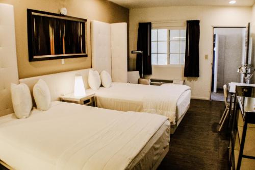 a hotel room with two beds and a window at Devonshire Inn Motel in Rosamond