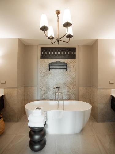 a bath tub in a bathroom with a chandelier at Burirattana Hotel-An Adults Only Hotel in Chiang Mai
