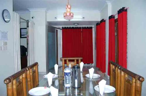 a dining room with a table and red curtains at Marry House in Dhaka