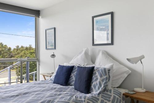 a bedroom with a bed with blue and white pillows at Magnum in Lorne