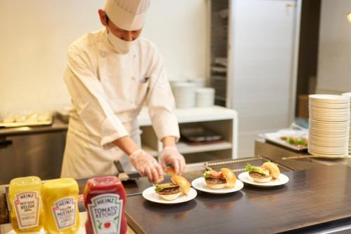 a chef preparing sandwiches on plates in a kitchen at Oriental Hotel Tokyo Bay in Urayasu