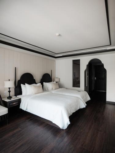 a bedroom with a large white bed with a large window at Burirattana Hotel-An Adults Only Hotel in Chiang Mai