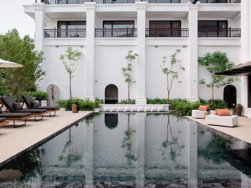 a pool in front of a building with chairs and a building at Burirattana Hotel-An Adults Only Hotel in Chiang Mai