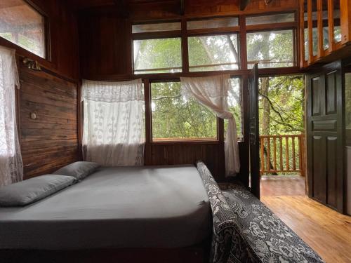 a bedroom with a bed in a room with windows at La Bromelia/Cabaña de Montaña, Cerro de la Muerte. in Cartago