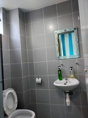 a bathroom with a toilet and a sink and a mirror at ANTZ Village Studio in Kampar