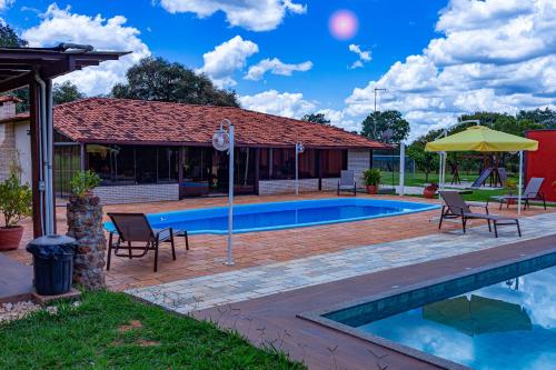 - une piscine avec des chaises et un parasol à côté d'une maison dans l'établissement Villaggio dos Pássaros, à Paranoá