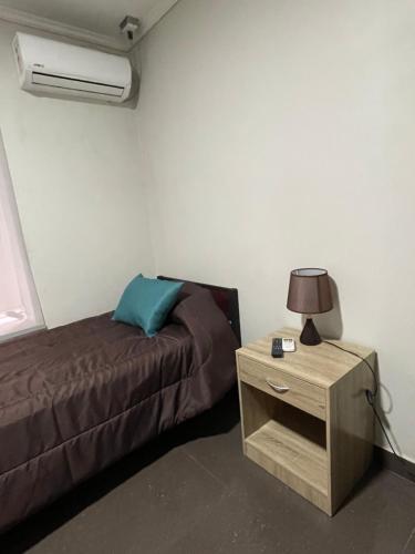 a bedroom with a bed and a night stand with a lamp at Residencial Astorga in Rancagua