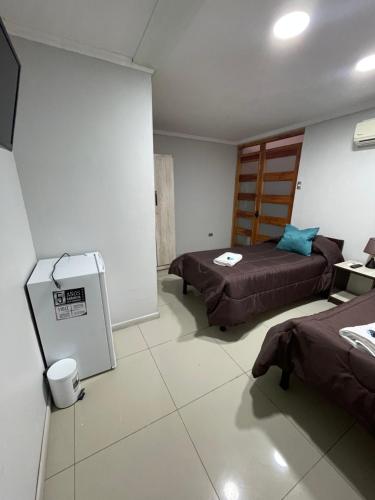 a room with two beds and a refrigerator at Residencial Astorga in Rancagua