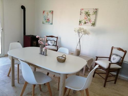 una sala da pranzo con tavolo e sedie bianchi di La Petite Maison Des Vignes 