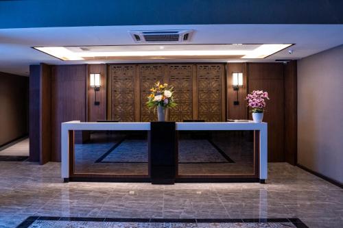 un vestíbulo con una mesa con flores. en CHRISTEE SUITES HOTEL en Melaka