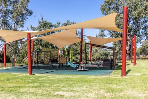 a park with a playground with tan roofs and red poles at 4 Pelican Court, Woodlane Mypolonga. in Mannum