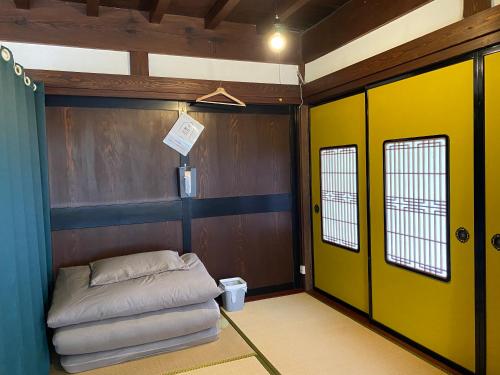 a room with a yellow wall and a door at 古民家ゲストハウス結舎-YUINOYA- in Nakanoto