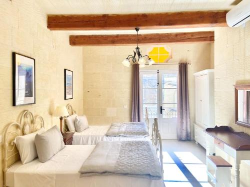 een slaapkamer met twee bedden en een raam bij Villa Rossa Gozo - 5 bedroom ensuite with pool & jacuzzi in Xewkija