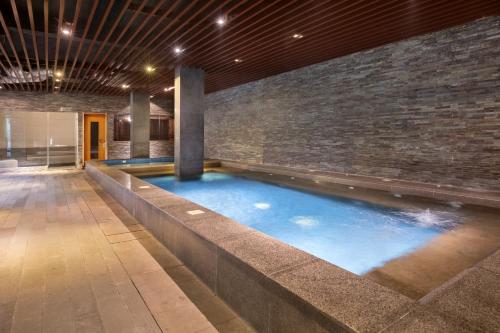 a swimming pool in a building with a brick wall at Novotel Palembang in Palembang