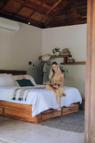 a woman sitting on a bed in a bedroom at Jati Kuta Lombok in Kuta Lombok
