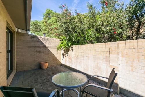 a patio with a table and chairs next to a brick wall at Bayview Number Two in Lorne