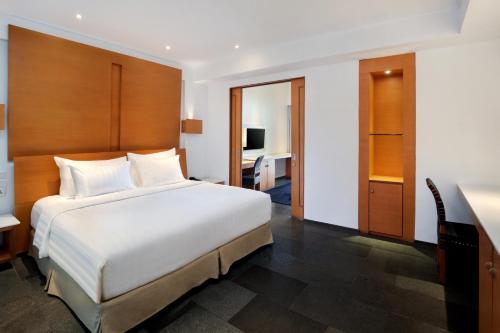 a bedroom with a large white bed and a desk at Novotel Palembang in Palembang