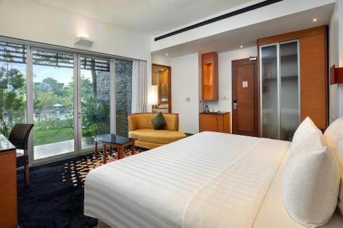 a bedroom with a large bed and a living room at Novotel Palembang in Palembang
