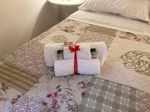 deux serviettes sur un lit avec un ruban rouge dans l'établissement Casa Vacanze: La casa di Gin, à Viterbe