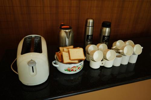 a counter top with a coffee maker and bread and cups at The Patio Thekkady in Thekkady