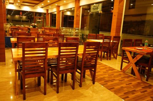a dining room with wooden tables and chairs at The Patio Thekkady in Thekkady