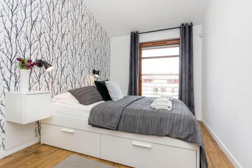 a bedroom with a white bed and a window at Grey Rentyear Apartments in Gdańsk