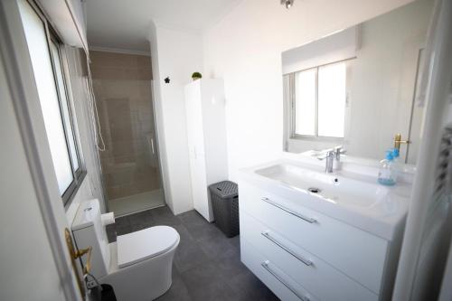 a white bathroom with a toilet and a sink at Ático en la plaza de Toro con garaje in Toro