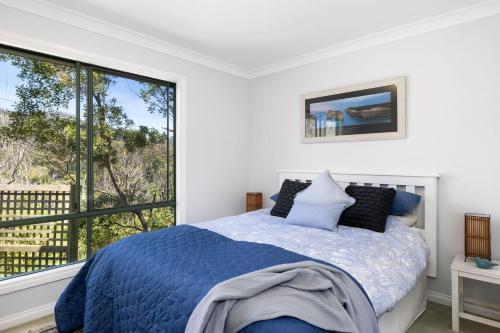 a bedroom with a bed and a large window at Tumbaramba in Wye River
