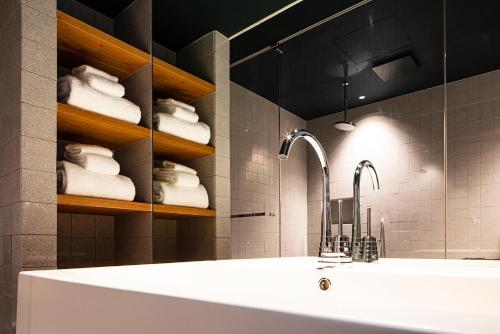 a bathroom with a tub and a sink and towels at SHIROIYA HOTEL in Maebashi