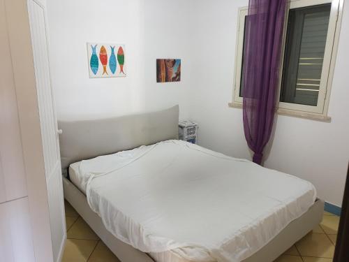 a white bed in a room with a window at Pretty Damuso Style Villa in Lampedusa
