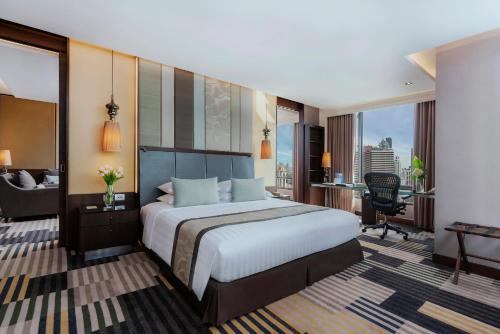 a hotel room with a bed and a desk and a chair at The Landmark Bangkok in Bangkok
