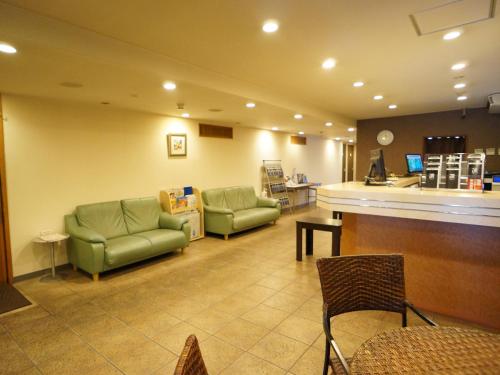 a waiting room with two green chairs and a counter at Kochi Green Hotel Harimayabashi in Kochi