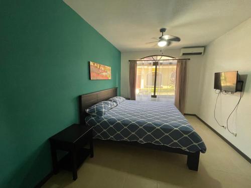 um quarto com uma cama e uma parede verde em Family oriented house just steps to the beach em Jacó