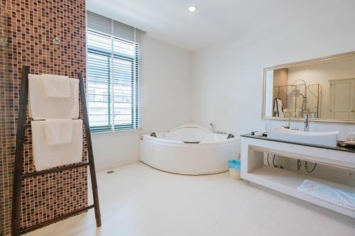 uma casa de banho com uma banheira, um lavatório e um espelho. em The Desiign Hotel - SHA em Si Maha Phot