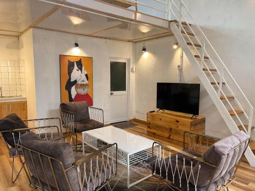 a living room with a television and a table and chairs at Dốc Garden Homestay - Apartment & Coffee in Da Lat