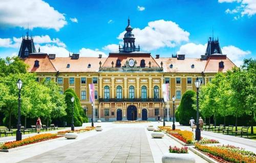 a large yellow building with a clock on it at Apartman Ljiljana LUX Sombor in Sombor