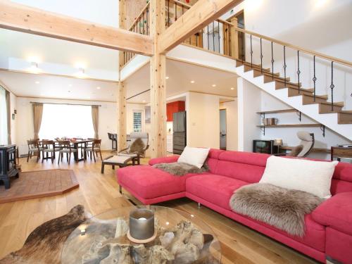 a living room with a red couch and a staircase at Villa Bavaria by Hakuba White Fox Company in Hakuba