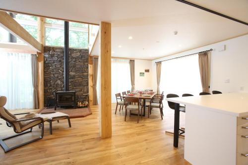 a dining room and living room with a stone fireplace at Villa Bavaria by Hakuba White Fox Company in Hakuba
