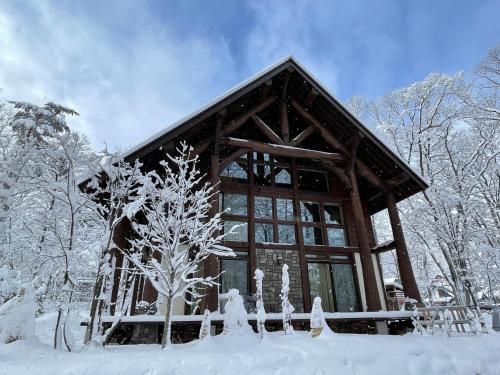 a log cabin in the snow with snow covered trees at Villa Bavaria by Hakuba White Fox Company in Hakuba