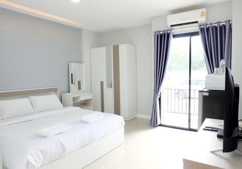 a white bedroom with a large bed and a window at Order Residence in Ban Pa Muat