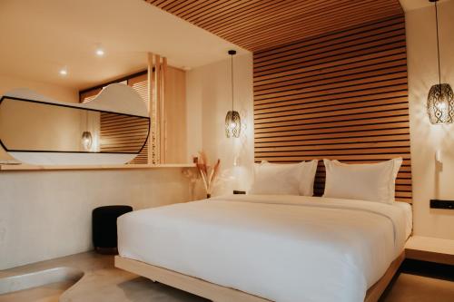 a bedroom with a large white bed and a mirror at Somnus Suites Parga in Parga