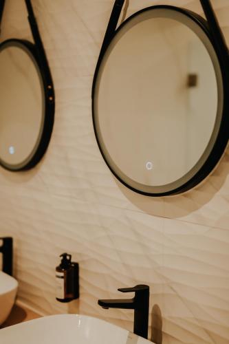 a bathroom with a sink and two mirrors on the wall at Somnus Suites Parga in Parga