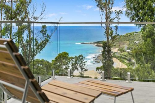 un banco de madera en una terraza con vistas al océano en Vue Sur La Mer, en Wye River