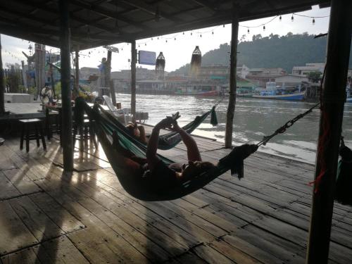 a person laying in a hammock on a dock at Rub Lom Chom Klong Homestay in Chumphon