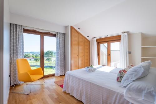 a bedroom with a large bed and a yellow chair at MA Maisons & Apartments Vista Alegre in Paxarinas