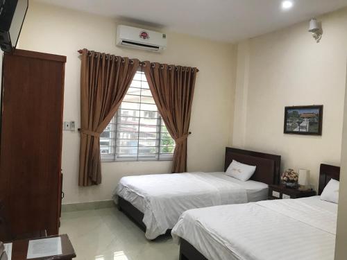 a hotel room with two beds and a window at Maily Hostel in Hue