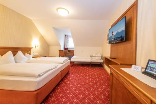 a hotel room with two beds and a flat screen tv at Hotel Gasthof Post in Nesselwang