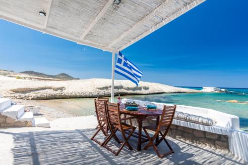a table and two chairs under an umbrella on a patio at Sarakiniko Boat House in Mandrakia
