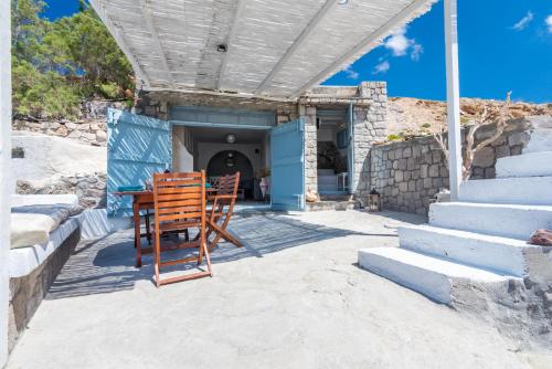 une table et des chaises en bois assises sur une terrasse couverte dans l'établissement Sarakiniko Boat House, à Mandrakia
